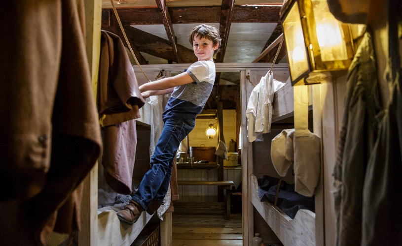 Boy climbing on beds in steerage on the SS Great Britain
